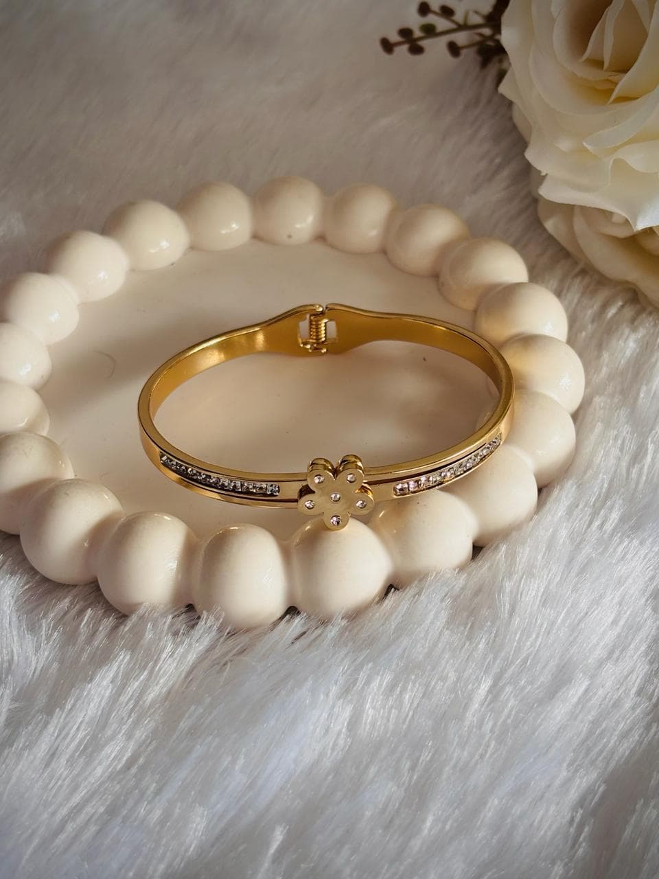 A gold-tone bangle. small flower-shaped charms