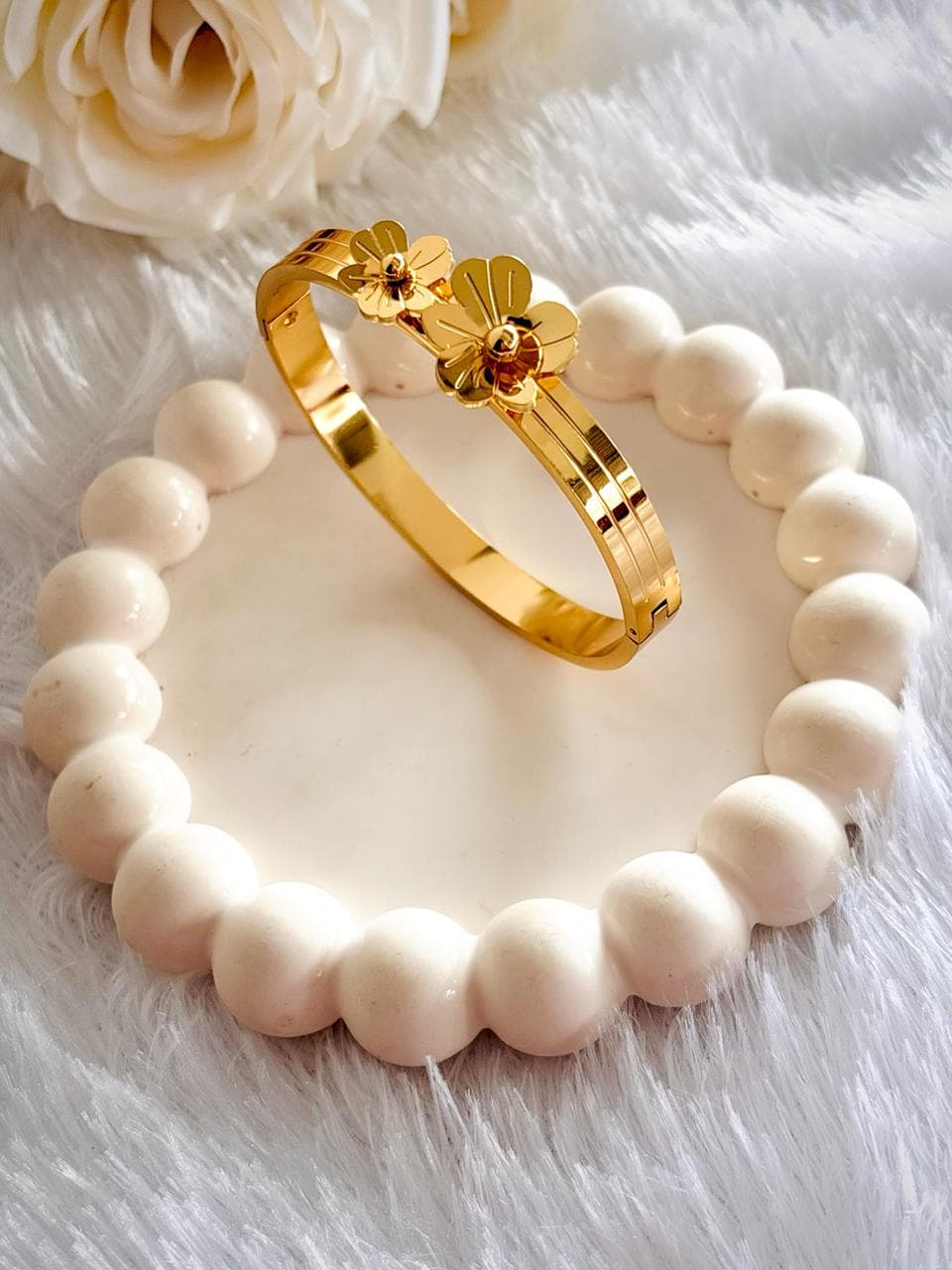 A gold colored bangle. Flower motifs